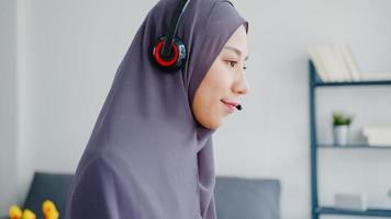 asiatische muslimische dame tragen kopfhörer webinar anhören online kurs kommunizieren per konferenz-videoanruf zu hause. Fernarbeit von zu Hause aus, soziale Distanzierung, Quarantäne zur Vorbeugung von Coronaviren. foto