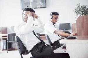 afroamerikanischer Kundendienstmitarbeiter mit Freisprech-Headset, der im Büro arbeitet foto