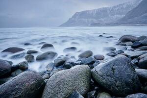 Wellen von norwegisch Meer wogend auf Stein Felsen. lange Exposition foto