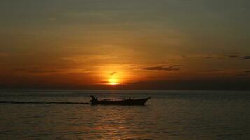 Silhouette von ein Boot auf das Meer beim Sonnenuntergang foto