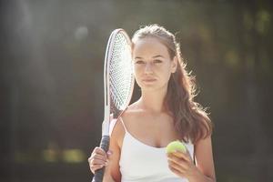 eine schöne frau, die einen tennisball in sportkleidung trägt. foto