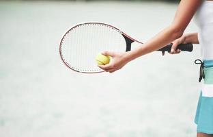 eine schöne frau, die einen tennisball in sportkleidung trägt. foto
