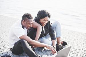 Zwei glückliche Freunde von Studenten oder Geschäftspartnern sitzen draußen und genießen einen Laptop