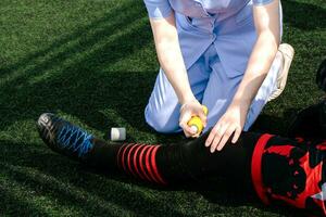 Krankenschwester ist Portion ein Fußball Spieler Wer verletzt seine Bein während spielen Fußball auf das Gras. foto