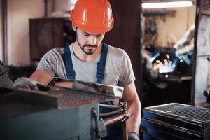 Porträt eines jungen Arbeiters mit Schutzhelm in einem großen Metallwerk. der ingenieur bedient die maschinen und fertigt teile für gasanlagen