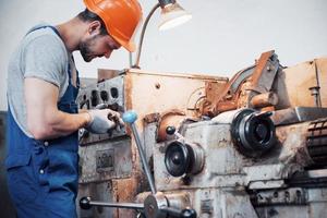 Porträt eines jungen Arbeiters mit Schutzhelm in einem großen Metallwerk. der ingenieur bedient die maschinen und fertigt teile für gasanlagen foto