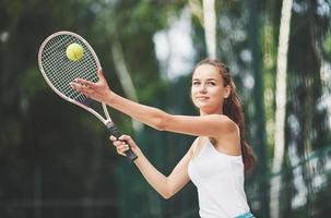 eine schöne frau, die einen tennisball in sportkleidung trägt. foto