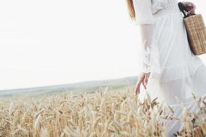 junges sensibles Mädchen im weißen Kleid posiert in einem Feld aus goldenem Weizen