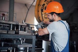 Porträt eines jungen Arbeiters mit Schutzhelm in einem großen Metallwerk. der ingenieur bedient die maschinen und fertigt teile für gasanlagen