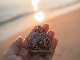 schließen oben von Jahrgang Tasche Uhr im Frau Hand mit Meer im das Sonnenuntergang Zeit wie Hintergrund. foto