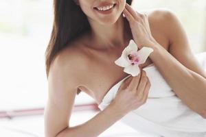 schöne Körperfrau mit weißer Blumenorchidee und Körperpflege. foto