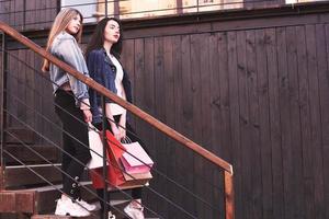 Zwei junge Frau mit Einkaufstüten beim Gehen auf der Treppe nach dem Besuch der Geschäfte foto