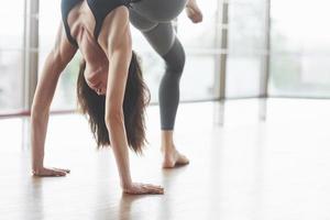 eine schöne Yoga-Frau, die in einem geräumigen, hellen Fitnessstudio praktiziert foto