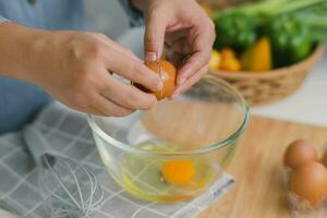 jung Frau Kochen im ein hell Küche, Hand gemacht geknackt frisch Ei Eigelb tropft in das Schüssel. vorbereiten Zutaten zum gesund Kochen. hausgemacht Essen foto