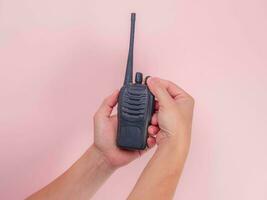 schließen oben Hand halten tragbar Walkie Talkie isoliert auf Rosa Hintergrund. schwarz Handheld Walkie Talkie foto