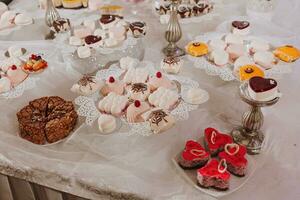 festlich Dessert Tabelle mit Süßigkeiten. Hochzeit Süßigkeiten Bar, verschiedene Kuchen, Pralinen auf steht. foto