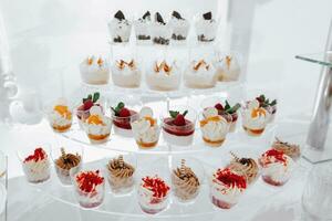 festlich Dessert Tabelle mit Süßigkeiten. Hochzeit Süßigkeiten Bar, verschiedene Kuchen, Pralinen auf steht. foto