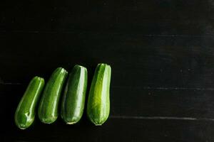 vier Grün frisch Zucchini auf ein schwarz Hintergrund. Konzept von gesund Essen foto