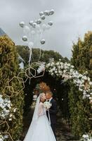 ein jung Hochzeit Paar beim ein Hochzeit Gemälde Zeremonie. das Braut und Bräutigam Kuss gegen das Hintergrund von Luftballons fliegend in das Himmel foto