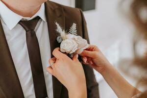 das zuerst Treffen von das Braut und Bräutigam auf das Hochzeit Tag. das Braut setzt ein Boutonniere auf das Bräutigam Jacke foto