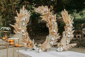 Hochzeit Zeremonien im das Park zum das Braut und Bräutigam. das Bogen ist gemacht von frisch Blumen und trocken Schilf. Weg Hochzeit Zeremonien. Stühle mit Gold Farbe foto