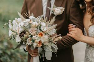 Nahansicht von ein Hochzeit Strauß im das Hände von das Braut und Bräutigam im Natur foto