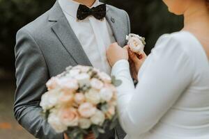 das zuerst Treffen von das Braut und Bräutigam. das Braut hängt an das Boutonniere zu das Bräutigam Jacke foto