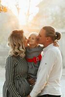 jung schwanger Frau mit Familie beim Sonnenuntergang im das Park foto