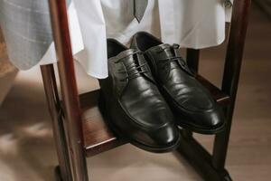 Einzelheiten von das Bräutigam auf ein hölzern Stand. schwarz Leder Herren Schuhe foto