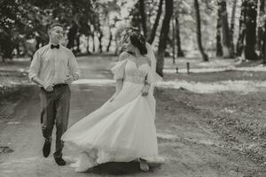 ein Hochzeit Paar, ein glücklich Braut und Bräutigam sind Laufen im das Park zu das Platz von das Hochzeit Zeremonie. Hochzeit Konzept foto