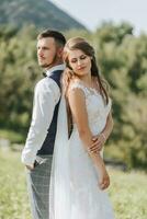 Porträt von ein stilvoll Bräutigam und Braut gegen das Hintergrund von Sommer- Berge. das Konzept von ein rustikal Hochzeit im das Berge, glücklich Bohemien Jungvermählten. foto