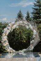 Hochzeit Zeremonie im das Hof. runden Bogen von Blumen und Geäst auf ein Grün Hintergrund. Hochzeit Thema. Urlaub Konzept foto