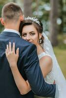 ein Hochzeit Paar ist genießen das Beste Tag von ihr Leben gegen das Hintergrund von hoch Bäume. Porträt von Bräute im Liebe im Natur foto