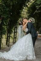 ein Hochzeit Paar ist genießen das Beste Tag von ihr Leben gegen das Hintergrund von Grün Blätter im das Park. Porträt von Bräute im Liebe im Natur foto