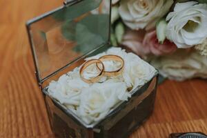 Foto von Hochzeit Zubehör. luxuriös Strauß von das Bräutigam. Gold Ringe auf ein Stand mit Blumen, auf ein hölzern Hintergrund.