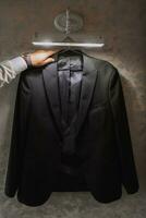ein des Mannes Jacke hängt auf ein Aufhänger, ein Geschäftsmann Mann nimmt es im seine Hände und bereitet vor zum ein Treffen foto