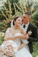 Bräutigam und Braut küssen im das Park. ein Paar von Frischvermählte, das Braut und Bräutigam, beim ein Hochzeit im Natur, ein Grün Wald, küssen, Foto Porträt. Hochzeit Paar