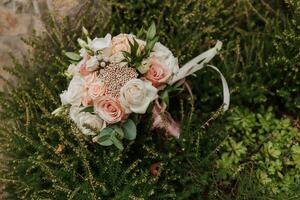 Hochzeit Strauß von Rosa Rosen, Gefieder und trocken Blumen auf das Steine im das Park foto