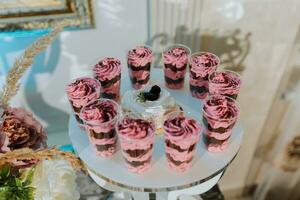 ein köstlich Hochzeit. Weiß Kuchen dekoriert mit Blumen. Süßigkeiten Bar zum ein Bankett. Feier Konzept. modisch Nachspeisen. Tabelle mit Süßigkeiten, Süßigkeiten. Früchte foto