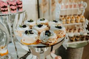 ein köstlich Hochzeit. Weiß Kuchen dekoriert mit Blumen. Süßigkeiten Bar zum ein Bankett. Feier Konzept. modisch Nachspeisen. Tabelle mit Süßigkeiten, Süßigkeiten. Früchte foto