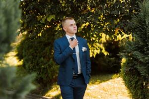das Bräutigam im ein Blau passen und Bogen Krawatte posieren im das Foto