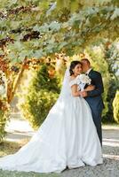 glücklich Braut und Bräutigam nach Hochzeit Zeremonie. lange Schleier. schick Weiß Kleid mit öffnen Schultern. ein Strauß von Orchideen. während Sonnenuntergang foto