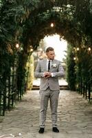 gut aussehend bärtig Mann, Bräutigam im grau passen und schwarz Krawatte Stehen draußen. Hochzeit Porträt. ein Mann im ein klassisch passen foto