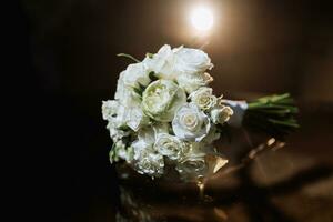 Zubehör auf das Bräutigam Hochzeit Tag. ein Strauß von Weiß Rosen auf ein dunkel Hintergrund mit Hintergrundbeleuchtung. Herren Mode foto