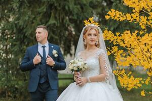 Bräutigam und Braut im Herbst Wald, Hochzeit Zeremonie, Seite Sicht. Bräutigam und Braut auf das Hintergrund von vergilbt Herbst Blätter. das Foto war genommen durch das Vergilbung Blätter von das Bäume