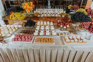 ein köstlich Hochzeit. Süßigkeiten Bar mit verschiedene Pralinen. Obst Tisch. Feier Konzept. modisch Nachspeisen. Tabelle mit Süßigkeiten, Süßigkeiten. foto