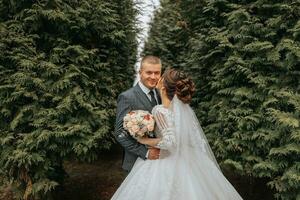 stilvoll Braut und Bräutigam zärtlich Umarmung und Kuss. schön Braut mit modern Strauß Umarmen stilvoll Bräutigam im Herbst Park. sinnlich romantisch Moment. Hochzeit. stilvoll und schöne. foto