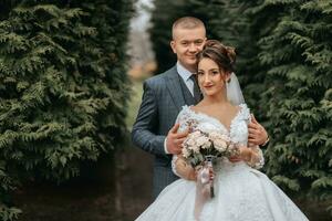 stilvoll Braut und Bräutigam zärtlich Umarmung und Kuss. schön Braut mit modern Strauß Umarmen stilvoll Bräutigam im Herbst Park. sinnlich romantisch Moment. Hochzeit. stilvoll und schöne. foto