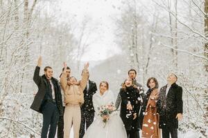 ein Gruppe von jung Menschen, freunde von das Braut und Bräutigam, werfen Schneebälle zusammen mit das Braut und Bräutigam im ein Märchen schneebedeckt Wald foto