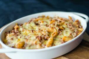 gebacken Pasta mit Käse im ein Weiß Gericht auf ein schwarz Hintergrund foto